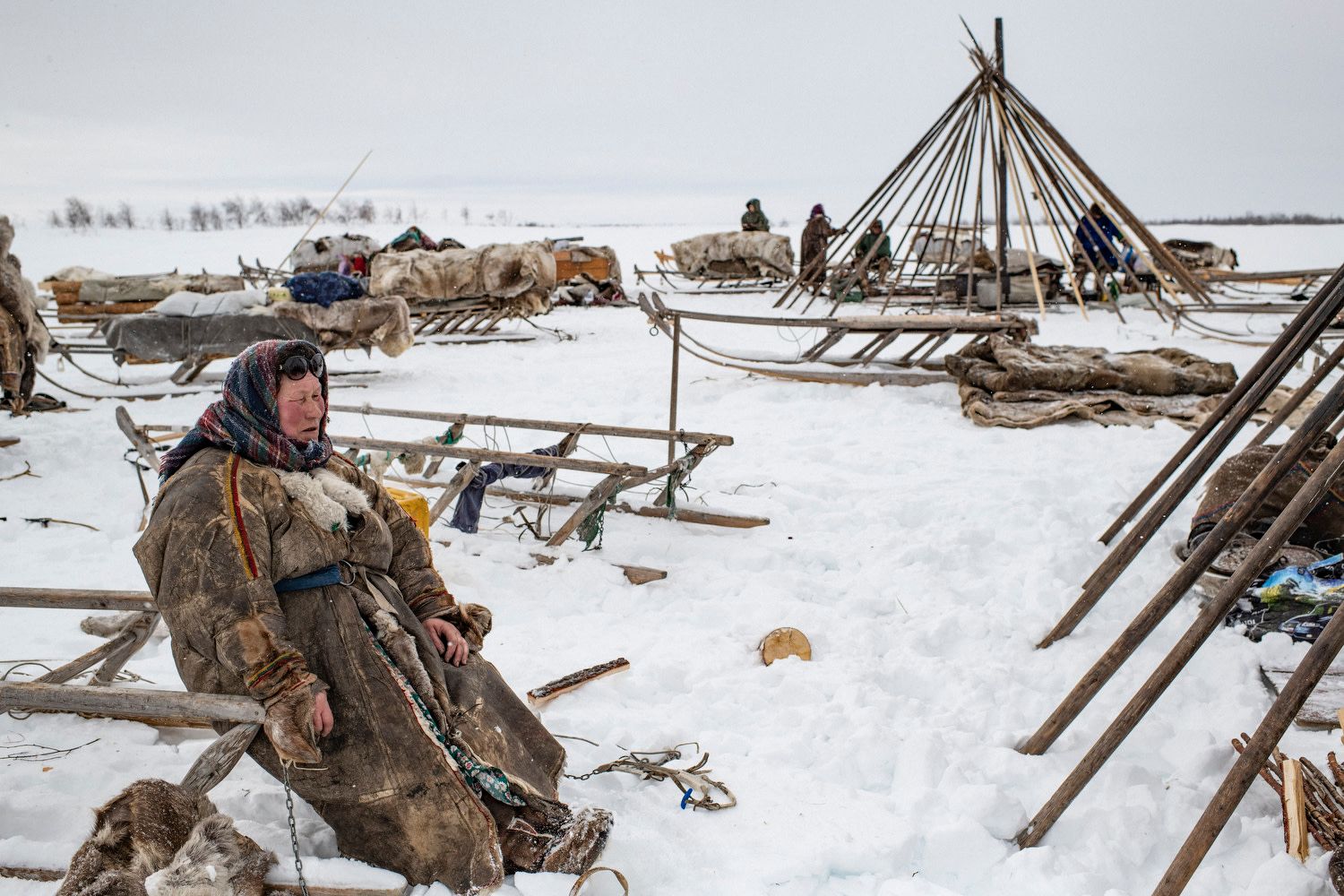 Yamal Peninsula, Yamalo-Nenets Autonomous Okrug, Russia, April 2018. An old woman from the Serotetto family takes a break after setting up her chum, a conical-shaped tent made of reindeer skins laid over a skeleton of long wooden poles. Each year, the Nenets people and their reindeers travel over a thousand kilometers.