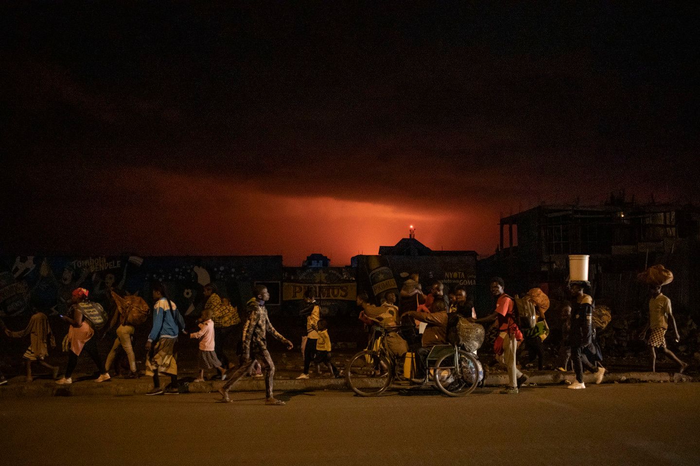 Goma, province du Nord-Kivu, mai 2021. Les habitants fuient l’éruption du Nyiragongo. Le Nyiragongo est l’un des volcans les plus actifs et les plus dangereux du monde. Le 22 mai 2021, il est entré en éruption et une énorme coulée de lave s’est arrêtée à peu de distance du centre de Goma et de son aéroport international, après avoir détruit 17 villages et tué au moins 32 personnes. Environ 20 000 habitants ont perdu leur maison. Le matin suivant, dès que la coulée s’est interrompue, beaucoup sont revenus en ville, mais plusieurs centaines de répliques sismiques ont affecté la population.